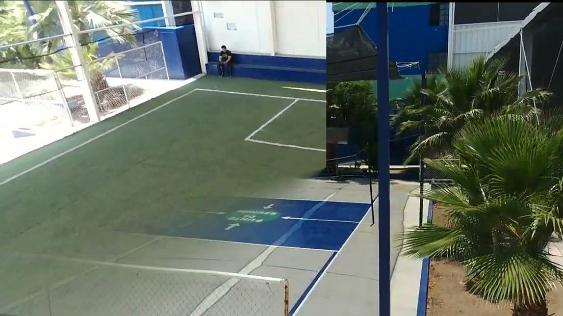 Cancha exterior vista desde el aire, con piso azul y verde, junto a palmeras.