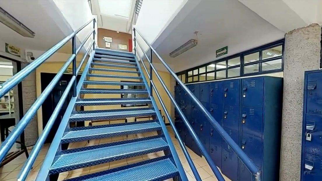 Escalera metálica azul junto a una fila de lockers azules.